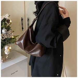 Detail of soft brown leather hobo bag featuring adjustable strap and metallic buckles