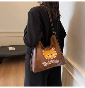 Détail d'un sac à bandoulière marron avec broderie ours et lettrage Bambha sur la sangle