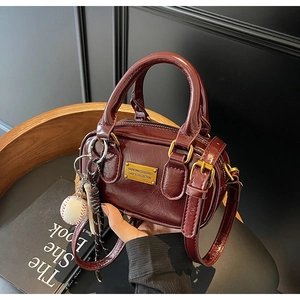 Detail of burgundy leather mini pillow bag with vintage texture and gold metal plaque