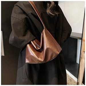 Close-up of deep brown glossy leather hobo bag showing soft texture and shoulder strap