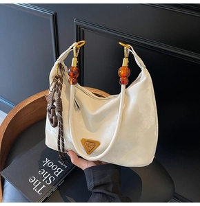 Detail of white leather shoulder bag with amber resin beads and metal triangle plaque