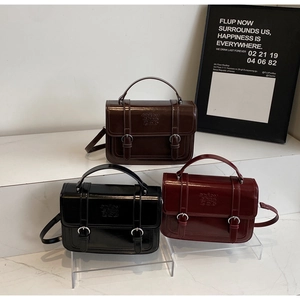 Detail view of retro Cambridge bags in dark brown, black and burgundy with metal buckles