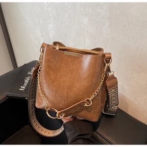 Détail du sac seau marron vintage avec bandoulière tissée et chaîne dorée