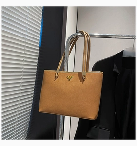 Detail of tan suede tote bag with elegant gold V-shape buckle and slim shoulder straps
