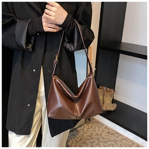 Detail of soft dark brown leather hobo bag with adjustable strap on a female model