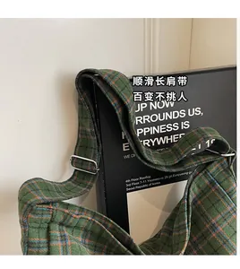 Detailed close-up of wide adjustable shoulder strap on green and orange plaid tote bag