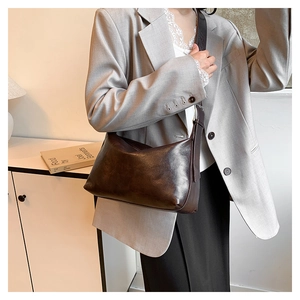 Retro dark brown leather shoulder bag shown on a model in a minimalist setting
