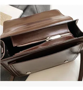 Close-up of vintage brown shoulder bag showing smooth zipper and magnetic flap closure
