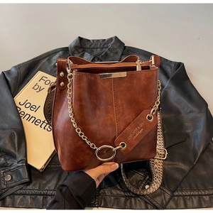 Détail du sac seau marron vintage avec une bandoulière tissée colorée et chaîne en métal