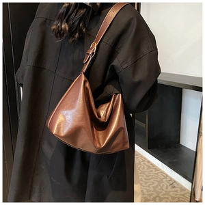 Detail of adjustable shoulder strap and glossy dark brown leather finish on hobo bag