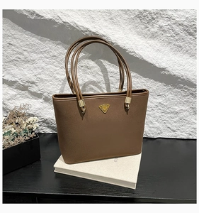 Close-up of the matte brown tote bag showing smooth leather texture and golden hardware