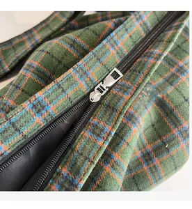 Close-up of smooth silver metal zipper on plaid tote bag with green and orange patterns