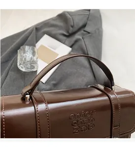 Detail of dark brown vintage faux leather handbag showing top handle and embossed text