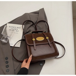 Détail du sac à dos rétro bicolore avec empiècements en daim et logo en métal doré