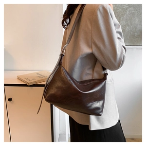 Detail view of smooth dark brown leather texture and silver buckle on shoulder bag
