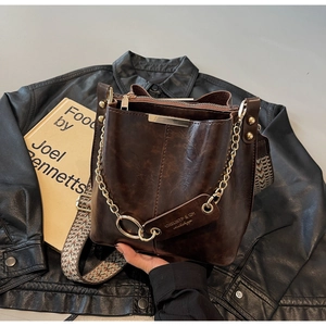 Détail d'un sac seau vintage marron foncé avec finitions dorées et large bandoulière