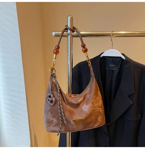 Detail of soft brown shoulder bag with beaded strap and gold triangular metal hardware