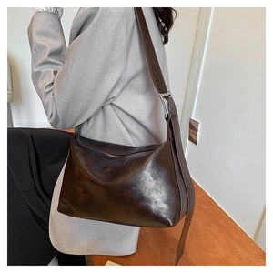 Close-up of vintage dark brown faux leather hobo bag worn by a model on the shoulder