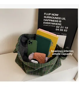 Detail showing the spacious interior of a green plaid tote bag with everyday essentials