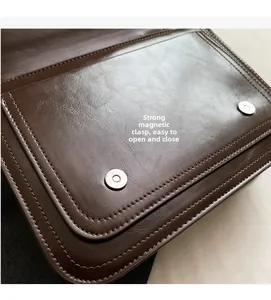 Detail of the vintage satchel showing magnetic buckle closure and brown faux leather texture