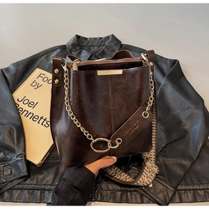 Détail du sac seau marron foncé avec chaîne dorée et bandoulière tissée ethnique