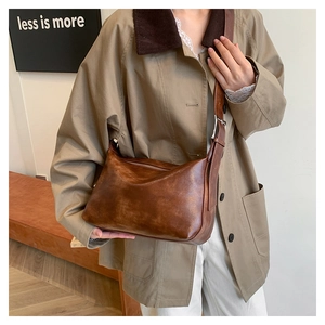 Close-up of vintage brown leather pillow bag with adjustable strap and metallic buckle