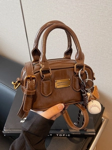 Glossy dark brown Boston mini bag with double handles and baseball charm accessories