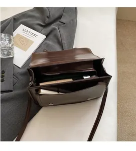 Internal view of brown patent leather crossbody bag showing spacious storage compartments
