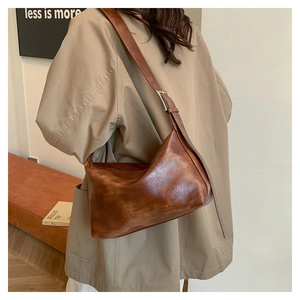 Detail of vintage brown leather crescent bag with adjustable strap and metal buckle
