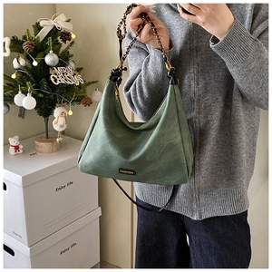 Detail of vintage green suede hobo bag with gold chain and fashion logo in Christmas setting