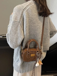Brown leather mini pillow bag with baseball charms shown on model in cozy sweater