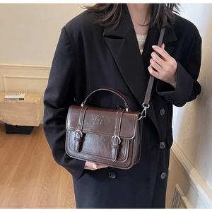 Detail view of a vintage brown leather crossbody bag with embossed lettering on the flap cover