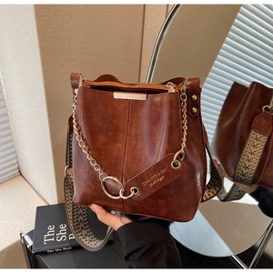 Détail du sac seau marron avec bandoulière tissée ethnique et chaîne dorée