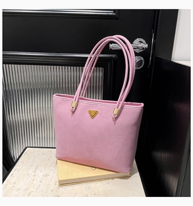 Detailed shot of pink suede tote bag with golden triangle hardware on stone surface