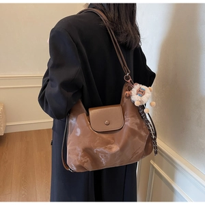 Detailansicht einer braunen Tragetasche mit glänzendem Finish und Schaf-Anhänger