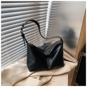 Detail of adjustable gold buckle and smooth black leather strap on a hobo bag