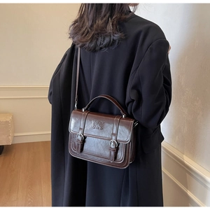 Close-up of vintage brown leather satchel with dual buckles and embossed detail