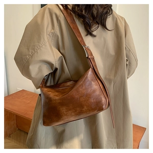Close-up of vintage brown leather hobo bag with adjustable silver buckle on shoulder strap