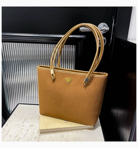 Detail of caramel suede tote bag with golden triangle logo on smooth leather trim
