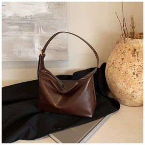 Detail view of smooth dark brown leather texture and stitching on minimalist Hobo bag