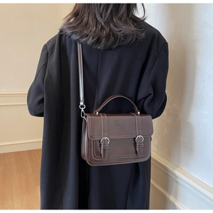 Detail of dark brown vintage handbag with top handle and embossed logo on the flap