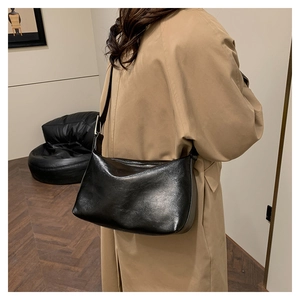 Model wearing a black glossy leather shoulder bag for chic daily commuting style