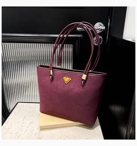 Close-up of burgundy suede tote bag with golden hardware and slender shoulder straps