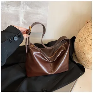 Detail of dark brown leather tote bag with gold buckle and smooth zipper closure
