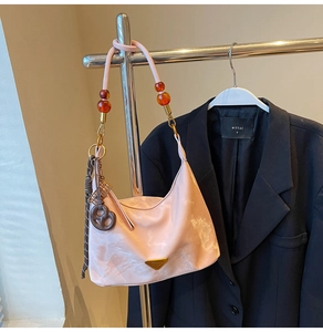 Pink nylon hobo bag with amber beaded strap and decorative pendant detail