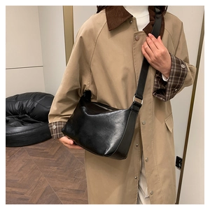 Detailed view of the black leather crossbody pillow bag worn on a model's shoulder