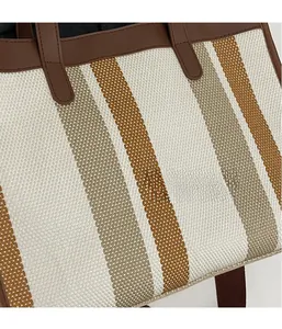 Close-up of three-color vertical stripe canvas tote with reinforced leather handle stitching