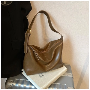 Close-up of a brown vintage leather shoulder bag with adjustable metal buckle on a suitcase