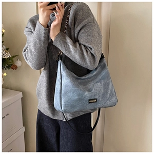 Detail of light blue faux suede tote with metallic FASHION tag and chain strap
