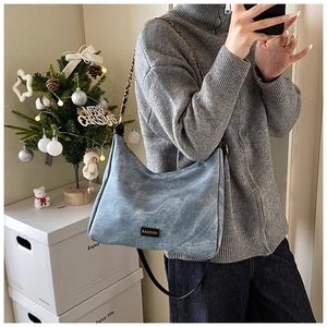 Detail of light blue denim texture tote bag with chain strap and fashion metal logo